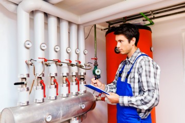 Junger Heizungs Techniker in Heizraum bei Heizanlage