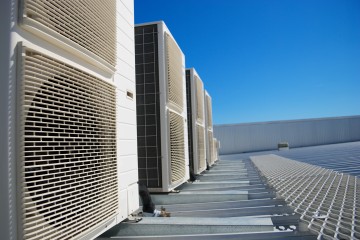 Air Conditioner units on the roof of an industrial building. Blue sky in the background. No people. Copy space.